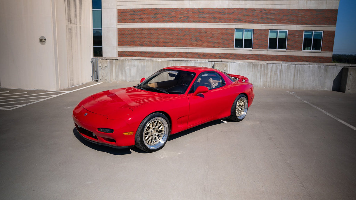 Red RX-7 FD on a rooftop parking deck