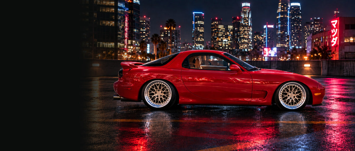 Red 1993 Mazda RX-7 FD side profile on a wet rooftop at night with a city skyline