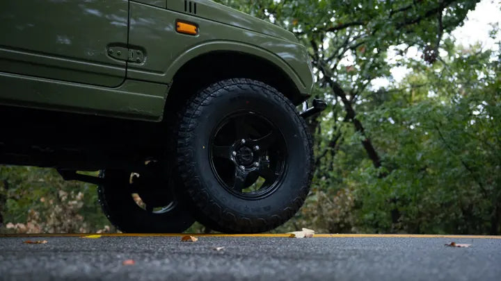 Black front wheel and off-road tire on the Suzuki Jimny