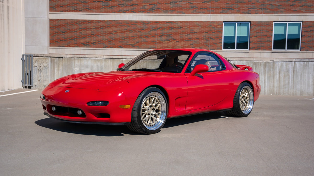 Front three-quarter view of the red RX-7 with gold BC Racing mesh wheels