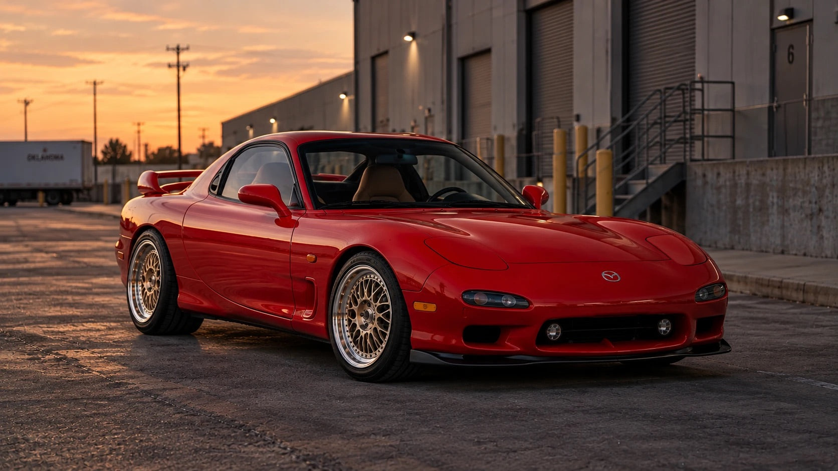 Vintage Red 1993 Mazda RX-7 on gold BC Racing mesh wheels outside a warehouse at sunset
